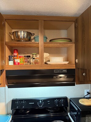 A kitchen with wooden cabinets, a black dishwasher, a stove, and a microwave. - Cozy 2-bedroom mobile home in Moorefield with AC/ WiFi (Moorefield)