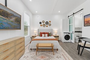 Ein modernes Schlafzimmer mit Bett, Nachttischen, einer Waschmaschine und einem Essbereich.