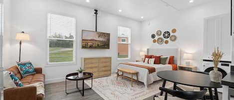 A modern living room with a sofa, a dining table, and a bed.