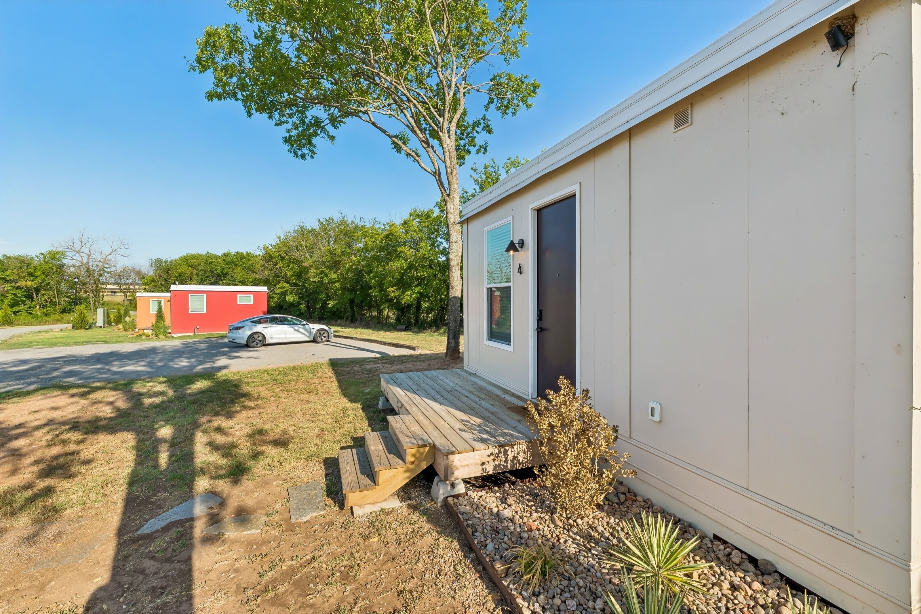Une maison mobile de plain-pied avec un porche à l’avant et une petite terrasse.