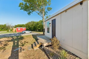 A single-story mobile home with a front porch and a small deck. - Modern Boxabl Casita | Stillwater OK | Pasadera 4 (Stillwater)