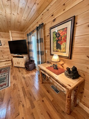 A wooden interior with a television, a bench with decorative items, and a framed picture on the wall. - Mountain Views - 4 BR/4BA - 3 Mi to downtown Gatlinburg & Rocky Top Sports World (Gatlinburg)