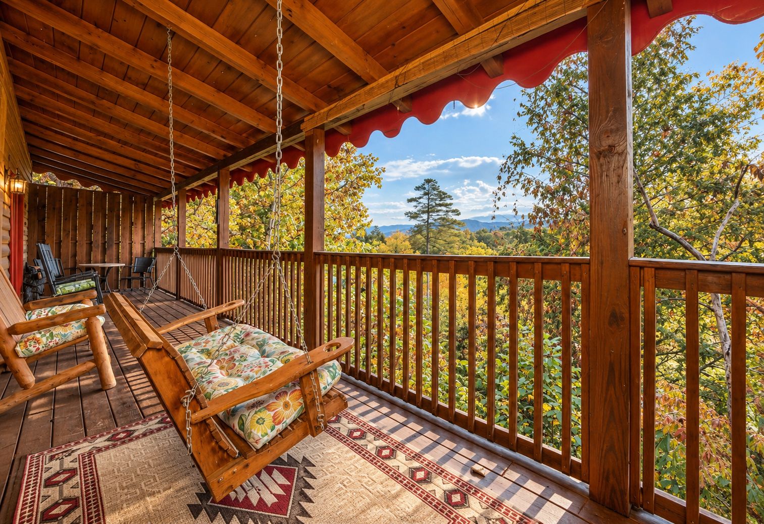 A covered porch with wooden flooring, a swing chair, and a view of autumn foliage.