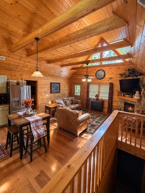 A cozy cabin interior with a dining area, seating, a fireplace, and a television. - Mountain Views - 4 BR/4BA - 3 Mi to downtown Gatlinburg & Rocky Top Sports World (Gatlinburg)