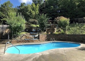 A swimming pool with a concrete deck, surrounded by trees and a stone wall. - Mountain Views - 4 BR/4BA - 3 Mi to downtown Gatlinburg & Rocky Top Sports World (Gatlinburg)