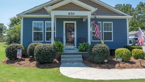 Uma casa residencial com uma placa numerada 470, um alpendre e duas bandeiras americanas.