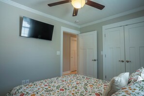 A bedroom with a bed, a ceiling fan, a television, and a wardrobe.