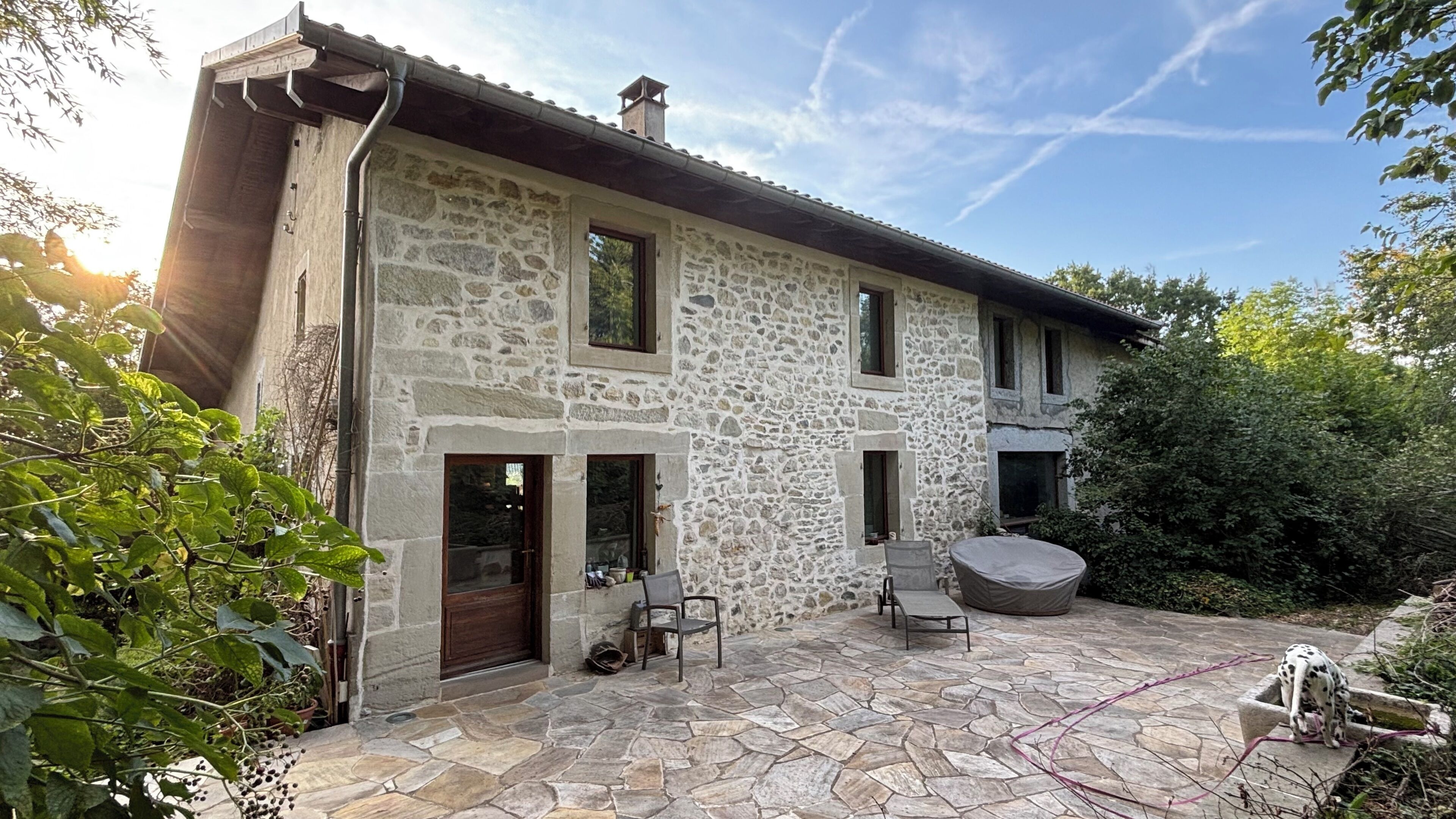 A stone house with a stone patio, a wooden door, and a small outdoor seating area.
