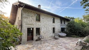 A stone house with a stone patio, a wooden door, and a small outdoor seating area.