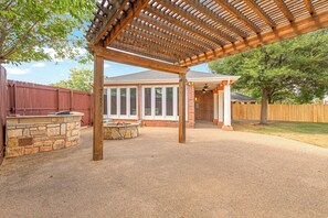 A covered outdoor patio area with a stone wall and a wooden fence. - Cozy Abilene Studio with Fireplace ~ Pet Friendly (Abilene)