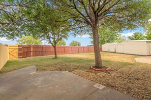 A backyard with a tree, a wooden fence, and a shed. - Cozy Abilene Studio with Fireplace ~ Pet Friendly (Abilene)