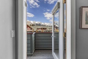 A balcony with a view of snow-capped mountains and a town below. - 2 bdrm penthouse with 180 Mountain view, heated pool & hot tubs (Canmore)