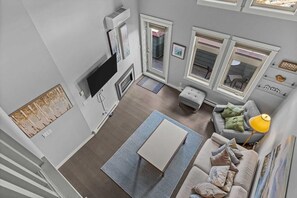 Ein modernes Wohnzimmer mit Flachbildfernseher, grauem Sofa, Couchtisch und einer Treppe, die zu einer oberen Etage führt.