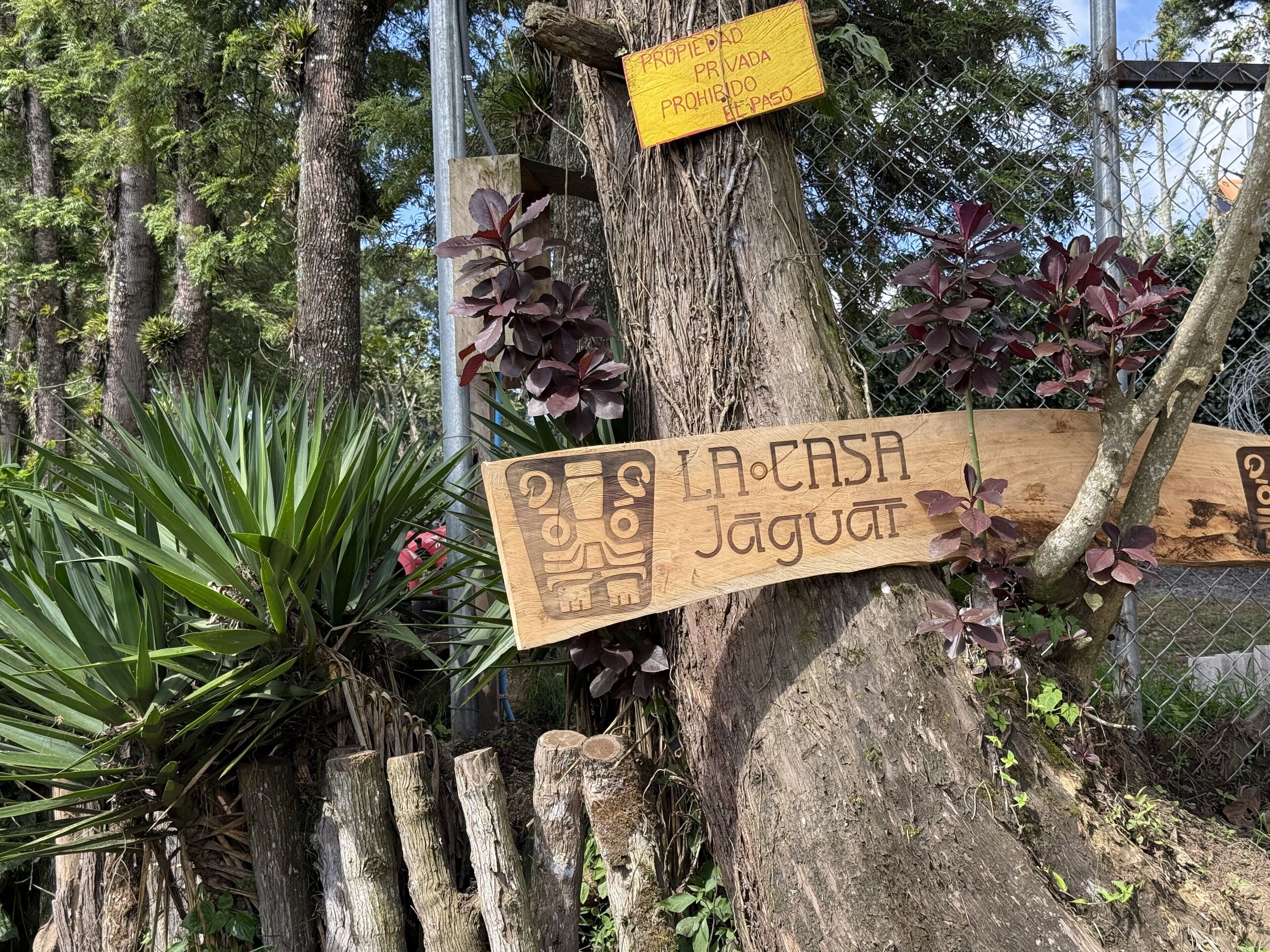A wooden sign with text, attached to a tree, and a yellow sign indicating private property.