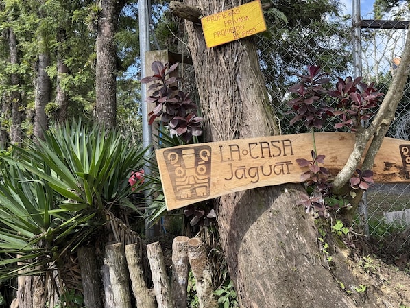 A wooden sign with text, attached to a tree, and a yellow sign indicating private property.