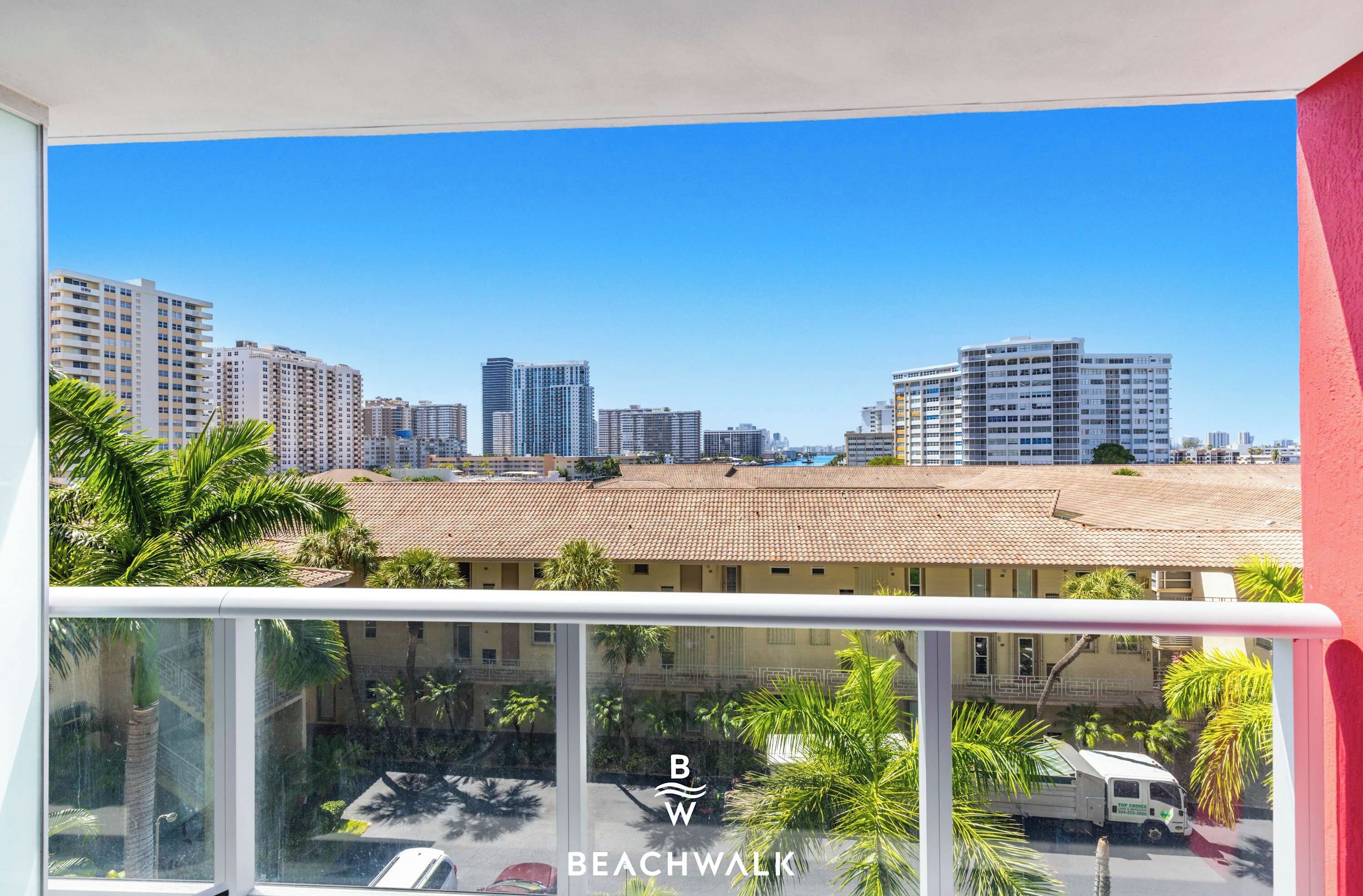 Un balcón con vistas a un paisaje urbano, que incluye edificios altos y una zona de playa.