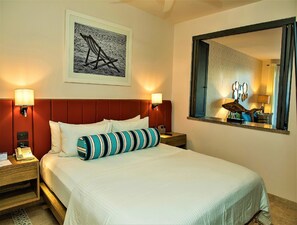 A hotel room with a large bed, two bedside lamps, a framed picture on the wall, and a mirror reflecting part of the room. - Explore the Beautiful Stretch of the Beach! Pet-friendly, Beachfront, Pools! (Cabo San Lucas)