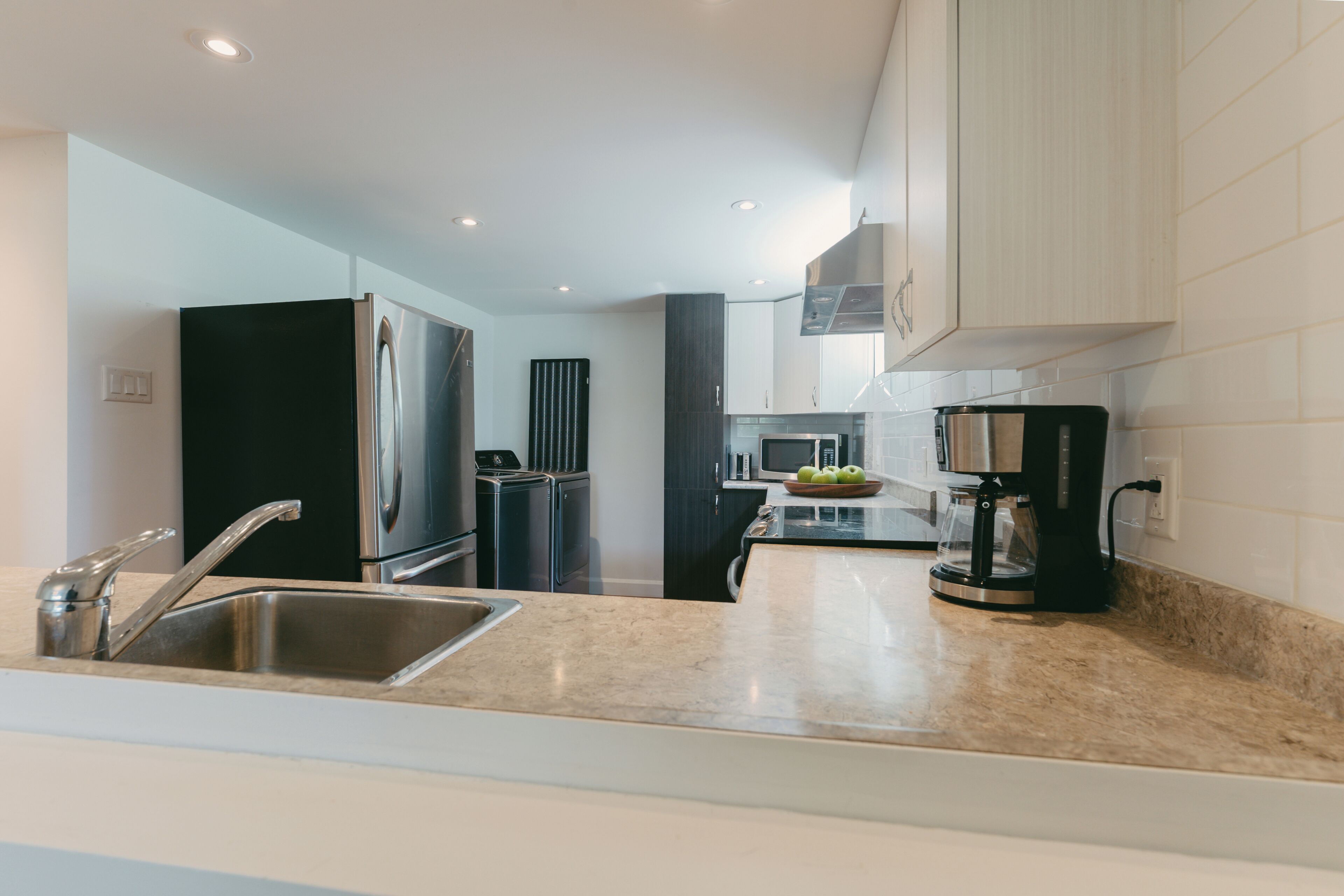 A modern kitchen with stainless steel appliances, a built-in oven, and a coffee machine.