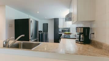Una cocina moderna con electrodomésticos de acero inoxidable, horno empotrado y cafetera.