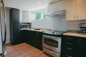 A modern kitchen with stainless steel appliances, dark cabinetry, and a window providing natural light.