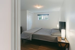 Una camera da letto con un letto, un comodino, una lampada, una finestra e una porta.