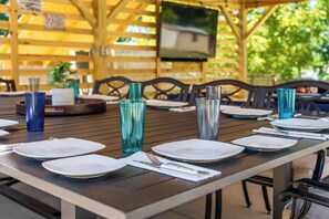 A dining area with tables set for four, each with white plates, cutlery, and blue glass tumblers. - Lakefront Oasis: Pool, Fire Pit, Kayak, Paddle Boards, Game Room (Hot Springs)
