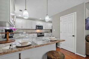 A modern kitchen with white cabinets, a granite countertop, and stainless steel appliances. - Lakefront Oasis: Pool, Fire Pit, Kayak, Paddle Boards, Game Room (Hot Springs)