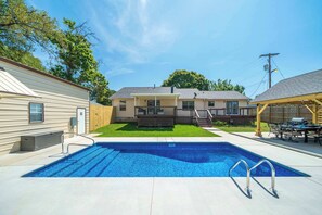 Ein Wohnhaus mit Swimmingpool, überdachter Terrasse und umzäunter Garten.