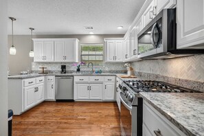A modern kitchen with white cabinetry, a stainless steel range, and a herringbone-patterned backsplash. - Lakefront Oasis: Pool, Fire Pit, Kayak, Paddle Boards, Game Room (Hot Springs)