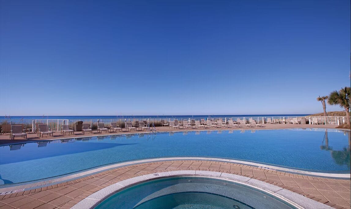 A pool with a view of the beach and ocean.
