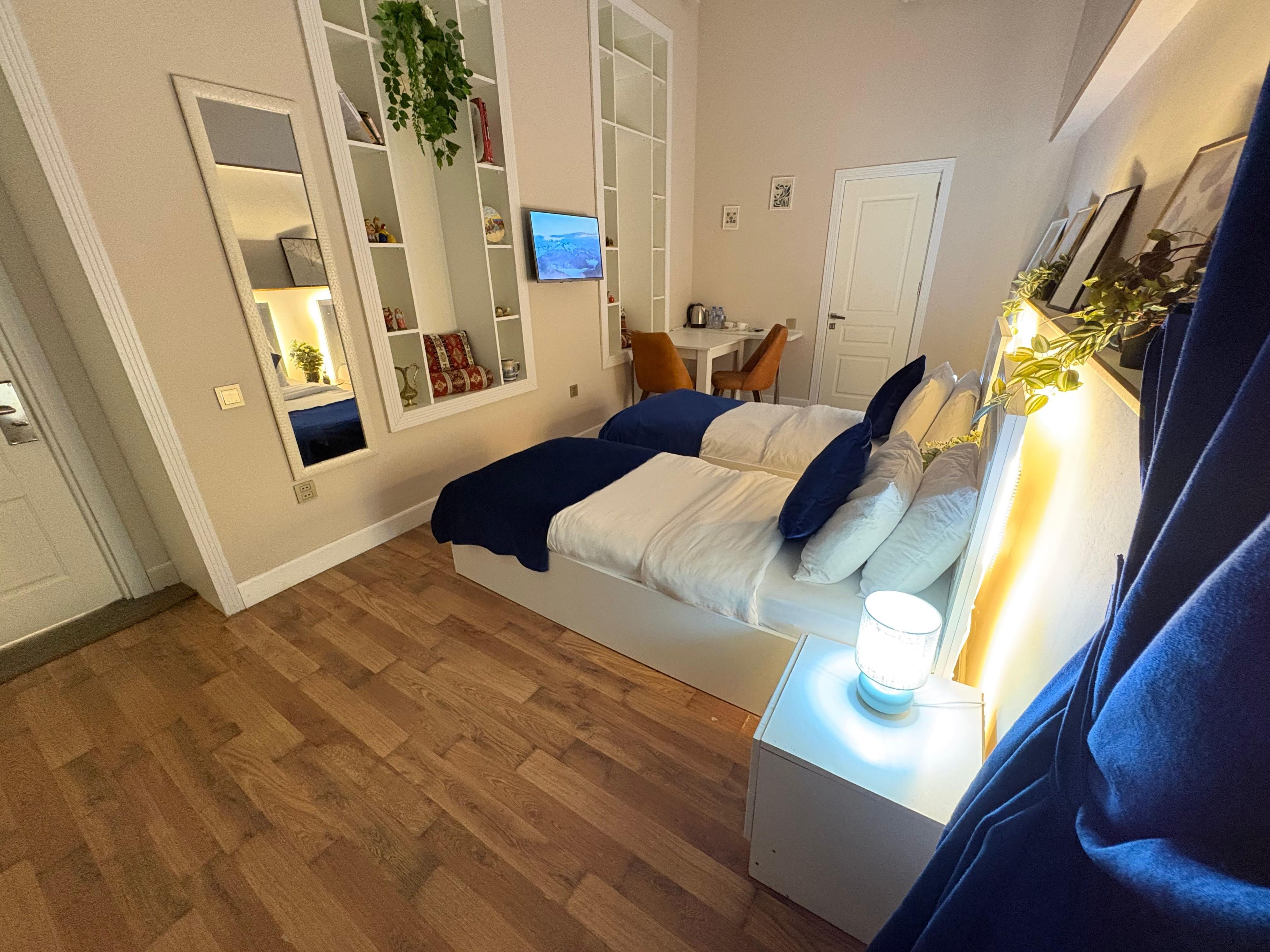 Un dormitorio con cama, mesita de noche y televisor montado en la pared.