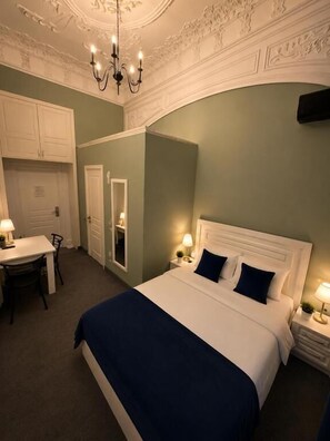 Una habitació d'hotel amb un llit, taules de nit, escriptori i una cadira.