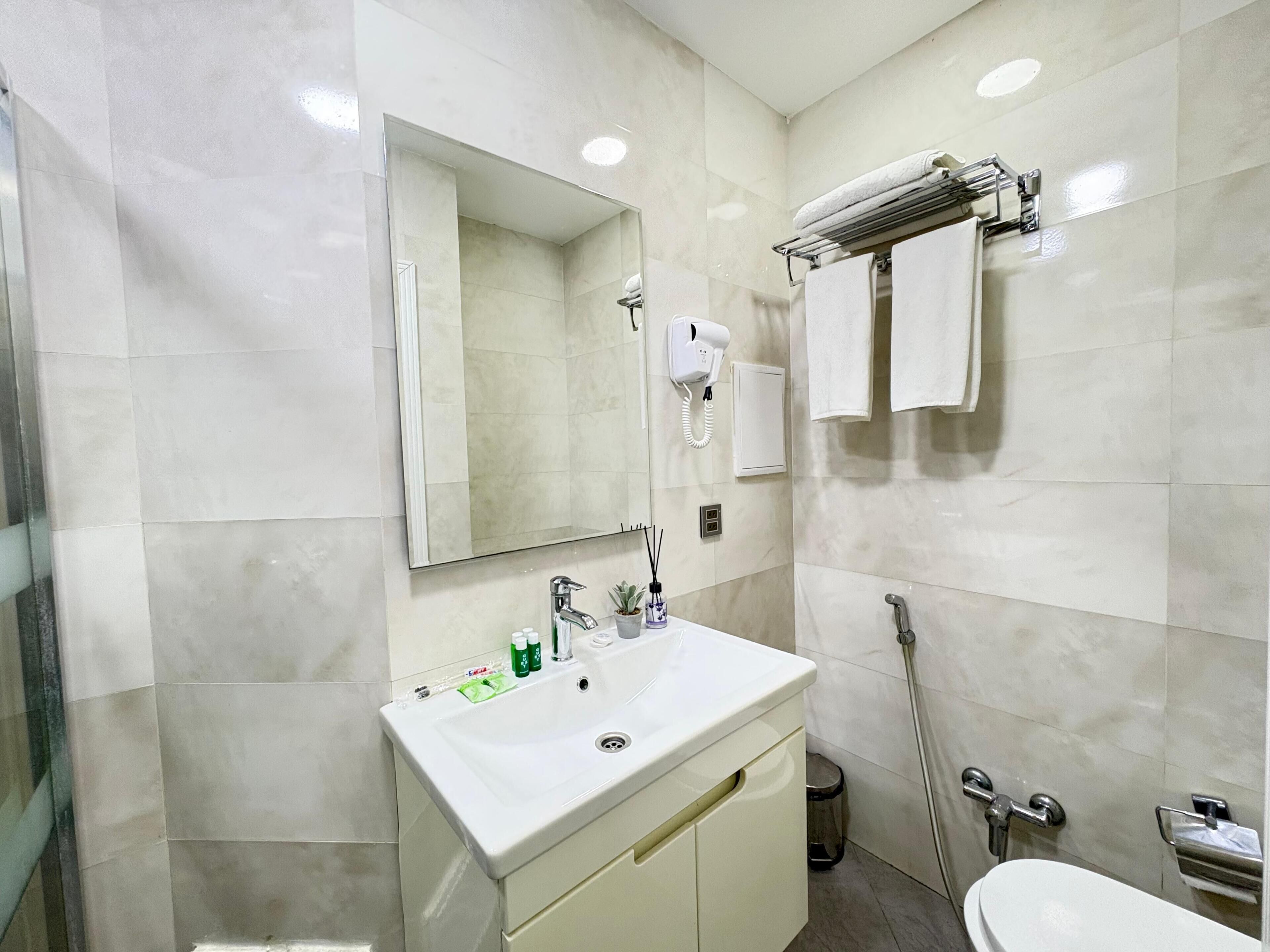 A modern bathroom with a white sink, mirror, and towel rack.