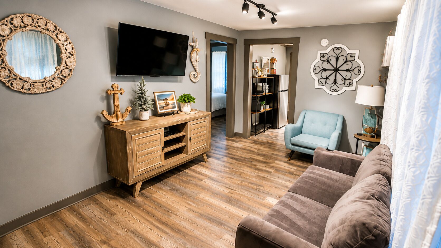 A living room with a wooden cabinet, a television, a blue armchair, and a sofa.