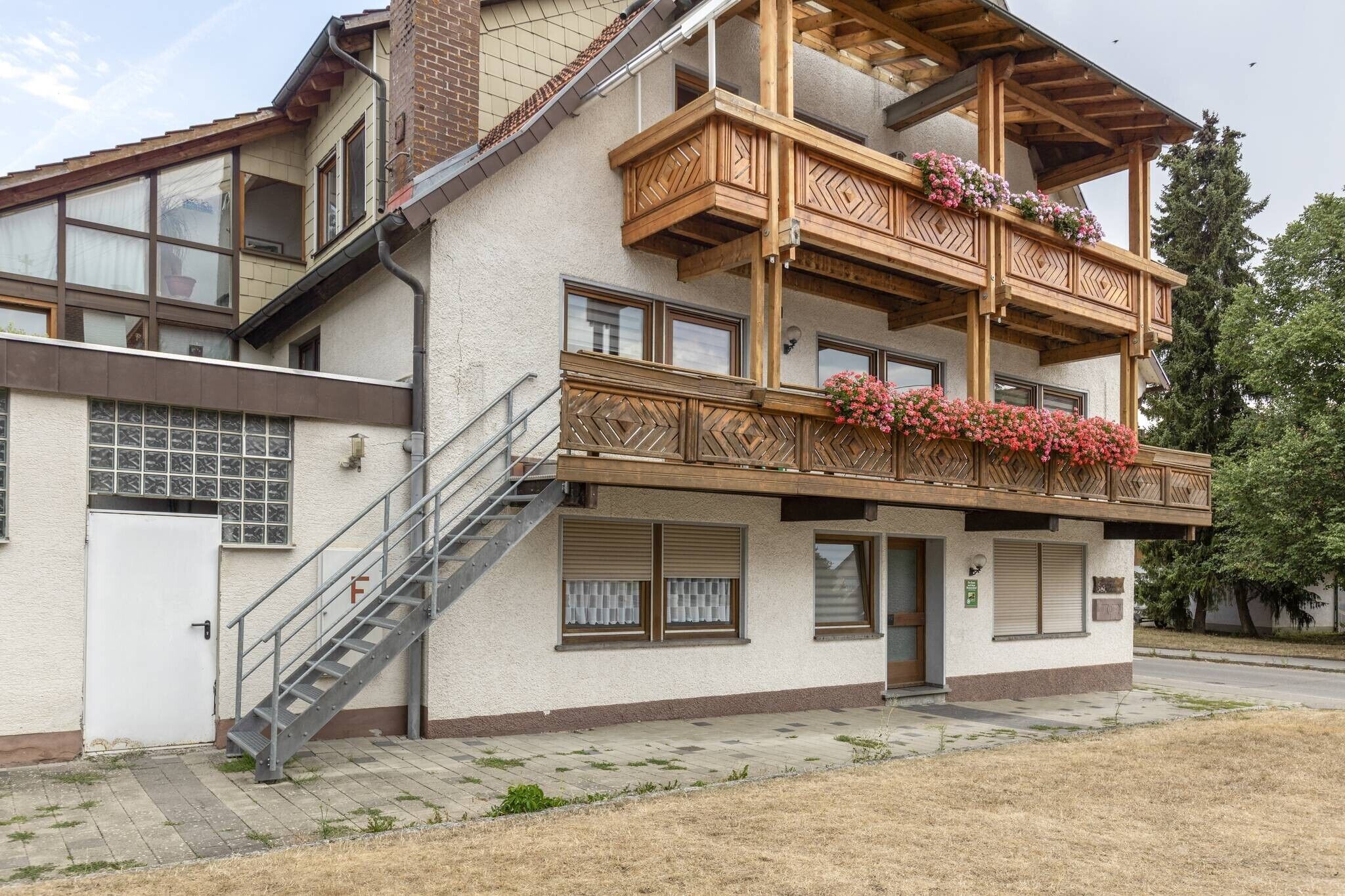 Ein mehrstöckiges Gebäude mit einem Balkon, einer Treppe und einer Tür, die mit einem 'F' gekennzeichnet ist.