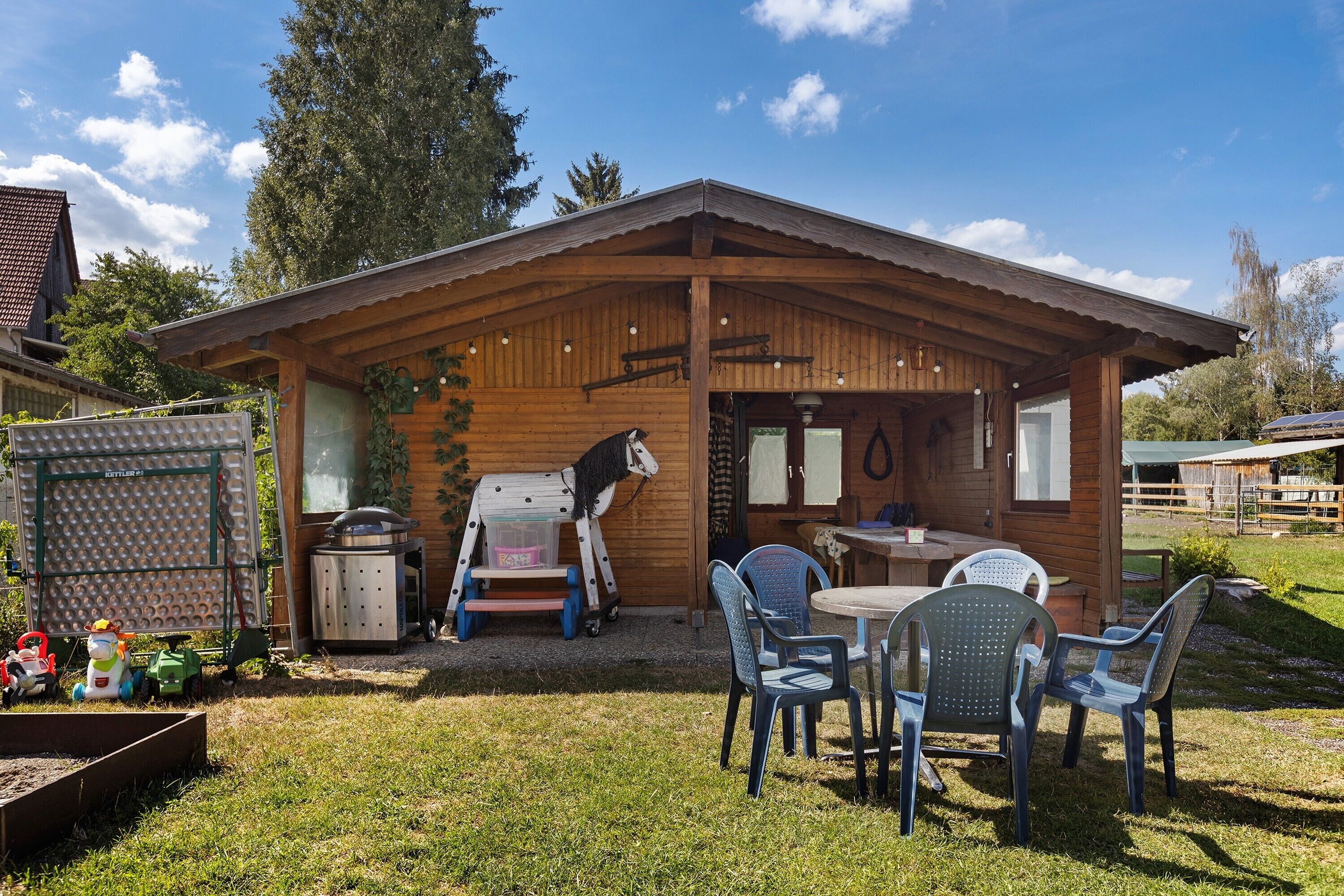 Une cabane en bois dotée d’un patio, d’une sculpture équestre et de sièges d’extérieur.