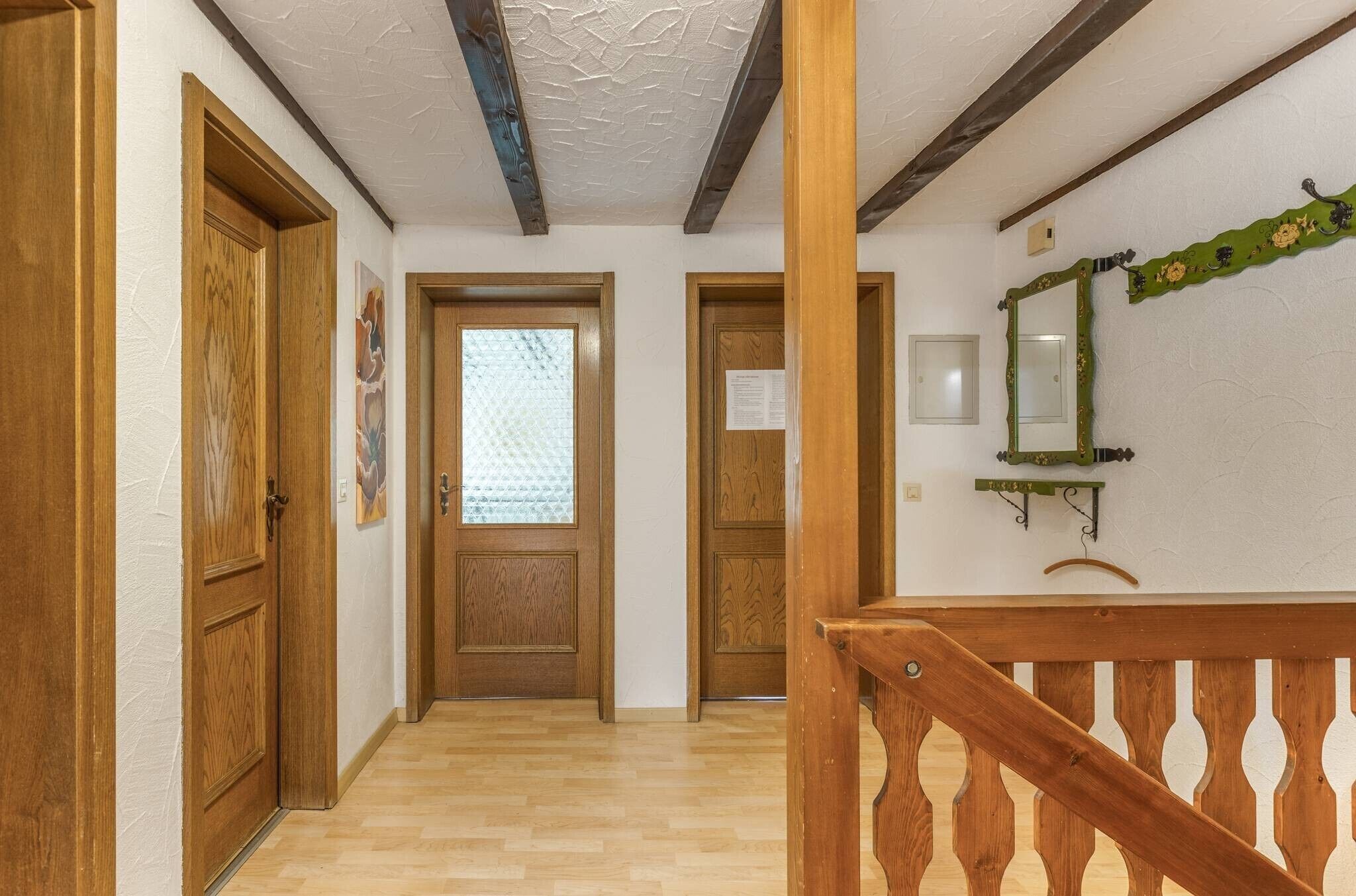 A wooden hallway with a wooden door, a glass door, and a staircase with a wooden railing.