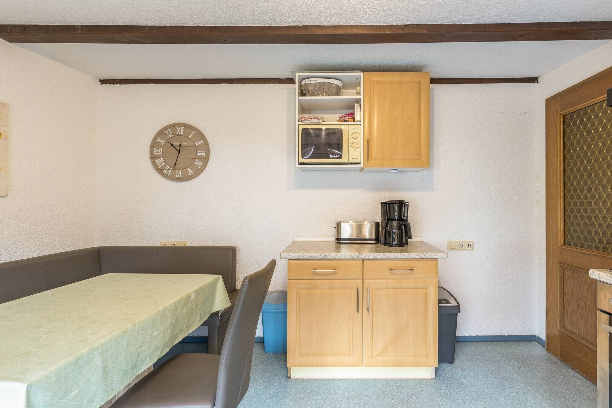 A compact kitchenette with a microwave, coffee maker, and wooden cabinets.