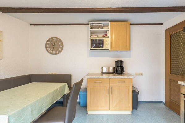A compact kitchenette with a microwave, coffee maker, and wooden cabinets.