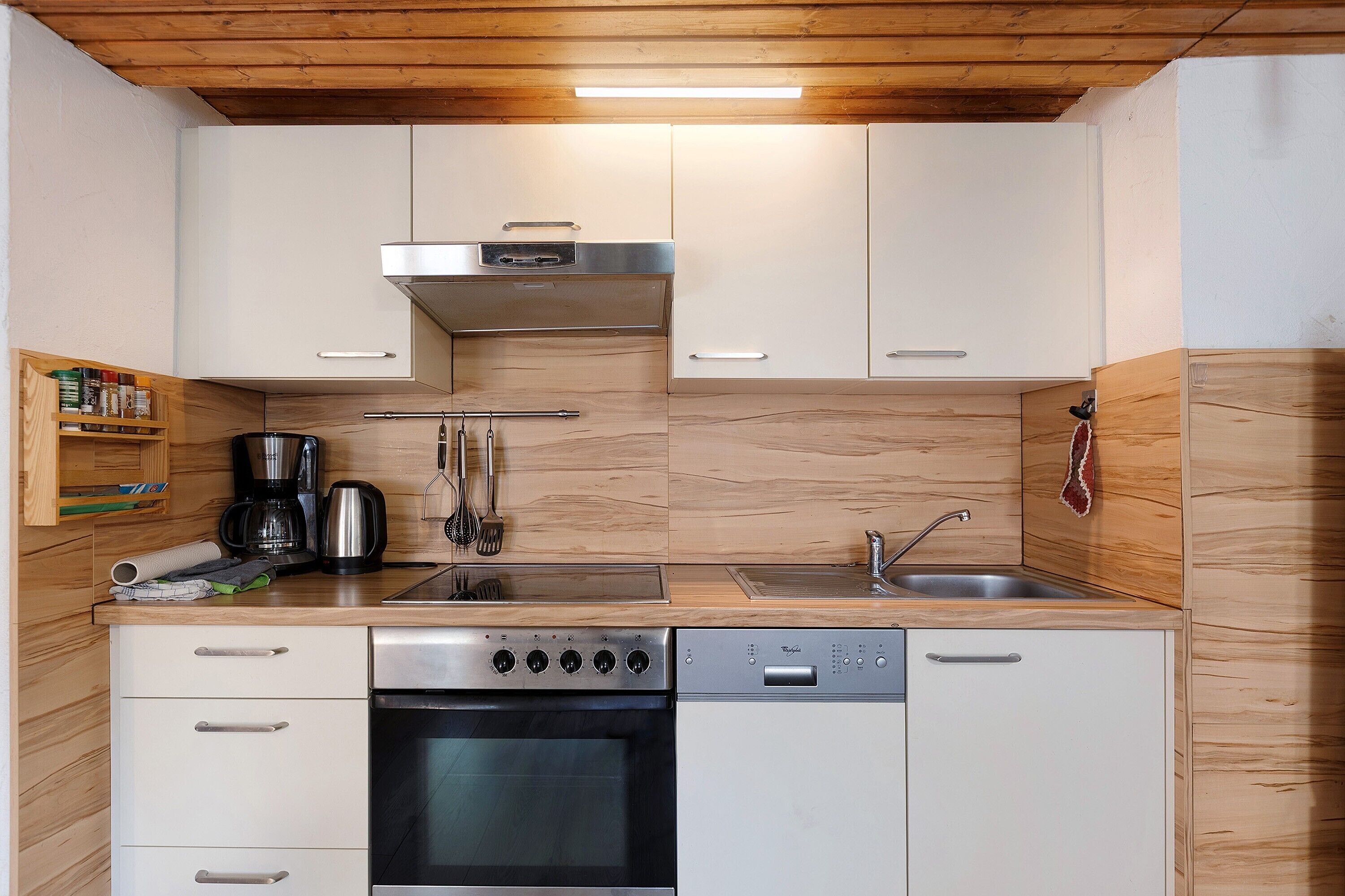 Eine moderne Küche mit Edelstahlgeräten, Holzschränken und einem eingebauten Backofen.