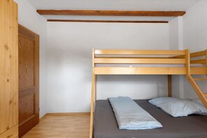 Una cama litera con estructura de madera, un colchón gris y dos almohadas.