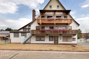 Un edificio de dos pisos con balcón, escaleras y chimenea.
