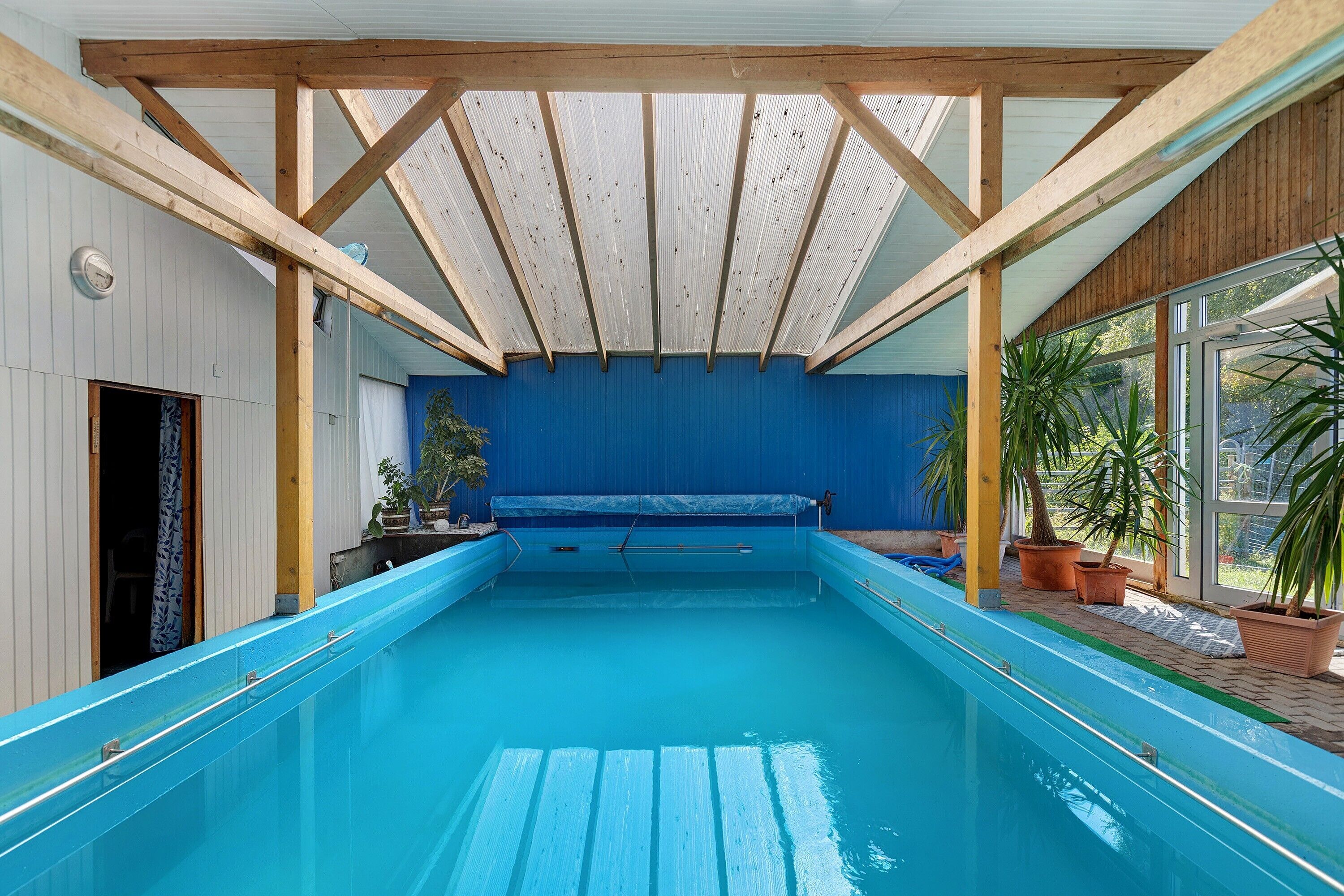 Ein Innenpool mit Holzbalkendecke und blauen Wänden.