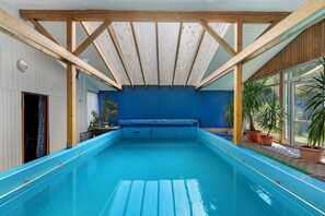 Una piscina interior con techo de madera y paredes azules.