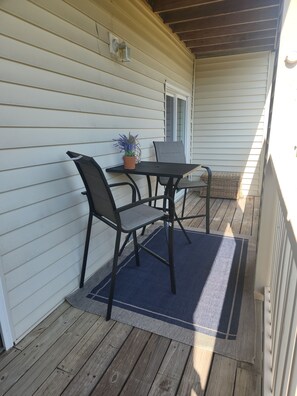 A covered patio with a table and chairs, a potted plant, and a wicker basket. - Cozy 2-bedroom condo in beautiful Surfside Beach with AC (Surfside Beach)