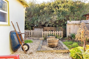 A garden with a wooden fence, a wheelbarrow, and a wooden tub. - Wine Country Bungalow 2Bd/1Ba (Lompoc)