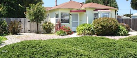 A single-story house with a red roof, a front porch, and a well-maintained lawn.