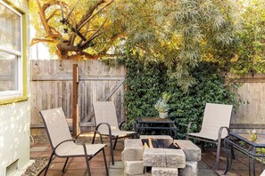 An outdoor patio with a fire pit, seating, and a wooden fence.