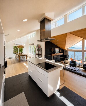 A modern kitchen with a central island, a dining area with a view, and a seating area with a view.