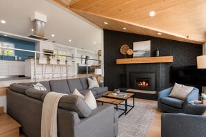 A modern living room with a fireplace, a sofa, a coffee table, and a TV.